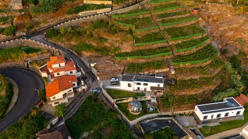 Le dôme de la Villa Domaterra I parmi les terrasses et les maisons au-dessus de Porto Moniz, vu du ciel