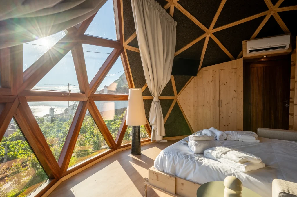 La chambre de la Villa Domaterra I dans la lumière du matin, les fenêtres triangulaires du dôme au-dessus du lit