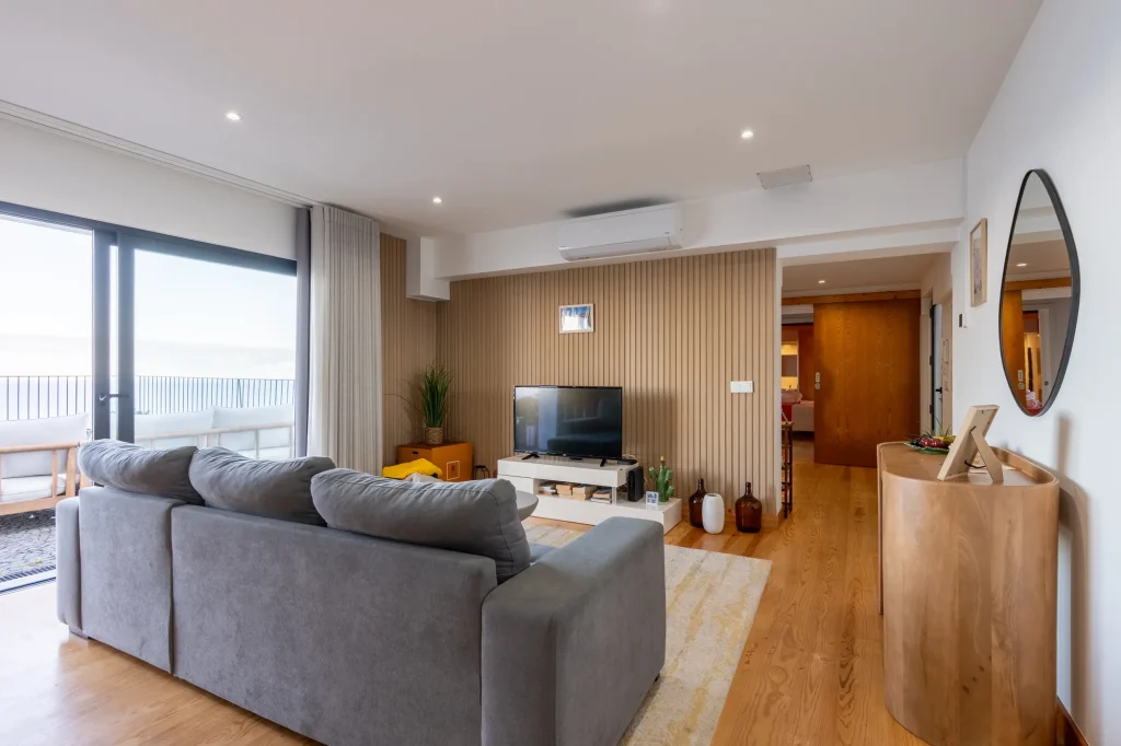 A sala de estar da Villa Escaleiras com sofá, televisão de parede e o corredor dos quartos ao fundo