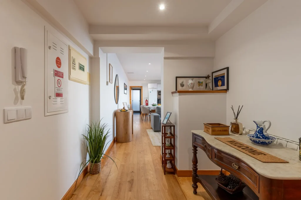 O hall de entrada da Villa Escaleiras, com uma consola, um jarro e um tapete 'Welcome'
