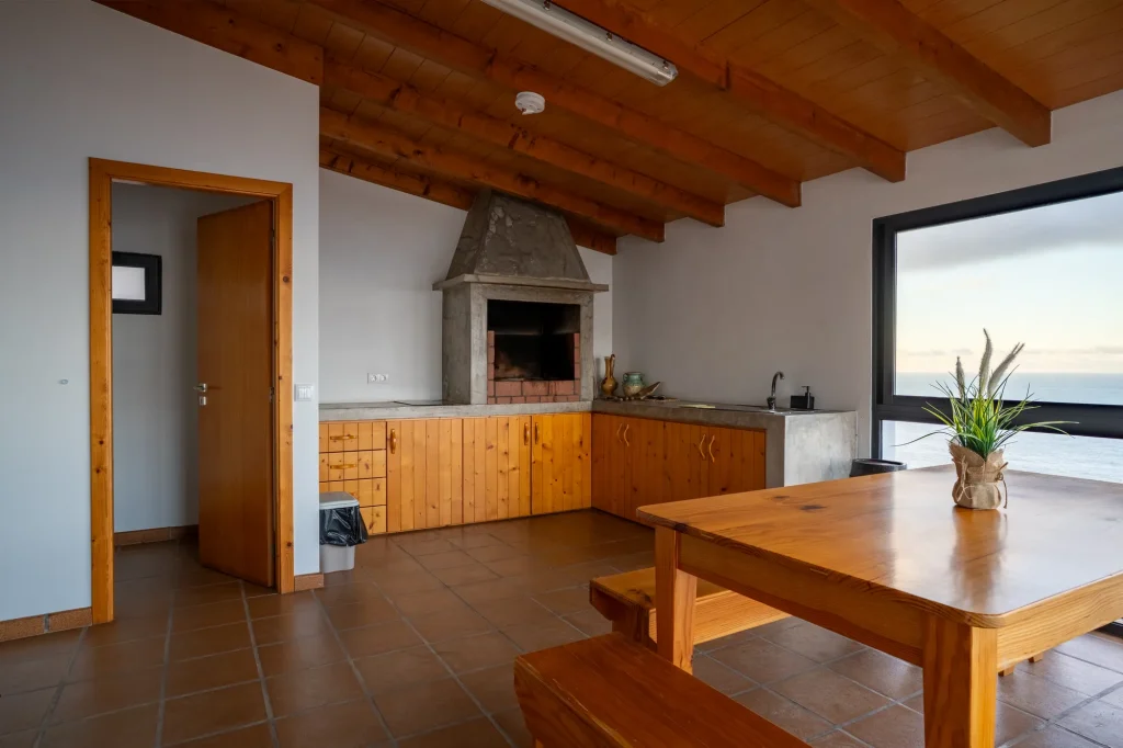 A cozinha exterior coberta da Villa Escaleiras, com um grelhador em pedra e mesa de jantar