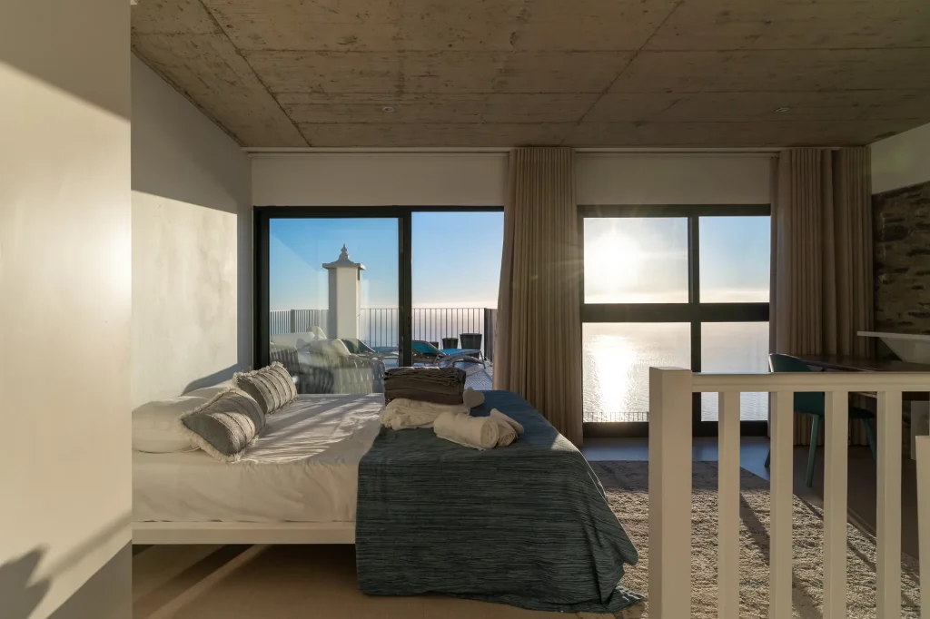 Villa Espigão's mezzanine bedroom, its bed facing floor-to-ceiling windows and the sea