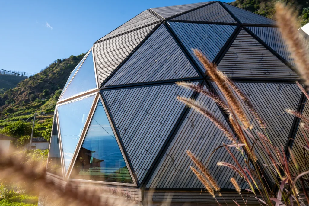 Villa Domaterra I's geodesic dome exterior, its timber and glass triangular panels against a clear blue sky
