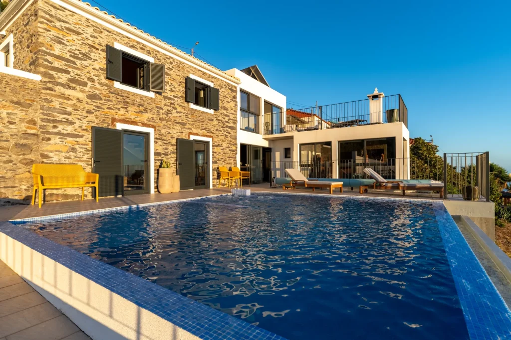 Villa Espigão's stone-and-white exterior and pool terrace under a clear sky