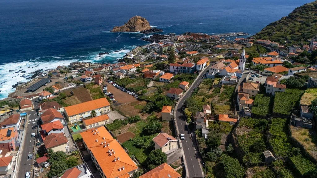 Aerial view of Porto Moniz, its orange-roofed village, church and islet, near Villa Domaterra II