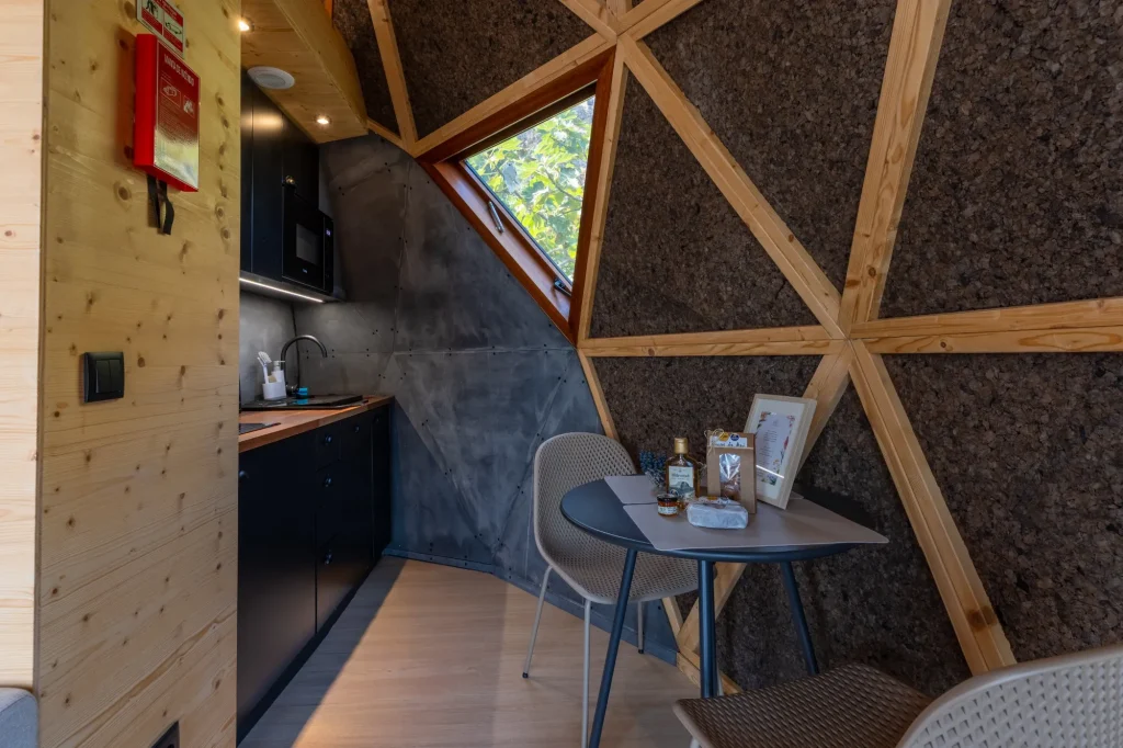 Villa Domaterra II's dining nook, a round table under a triangular window in the dome's cork-and-timber wall, the kitchenette beside it