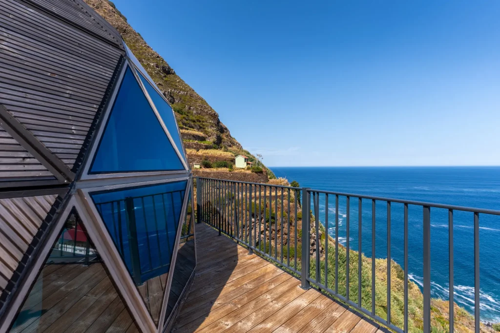 Villa Domaterra II's timber and blue glass geodesic dome on its wooden deck, the railing running out towards the Atlantic beneath a terraced hillside
